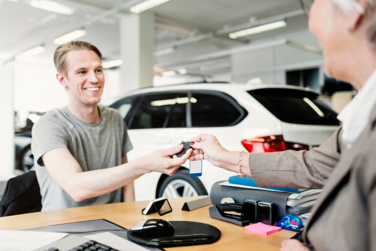 Happy Man Receiving Car Keys Saleswoman Desk